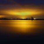 Lichtverschmutzung und Lichtabschaltungen 5 See bei Sonnenuntergang mit goldenen Lichtern am Horizont